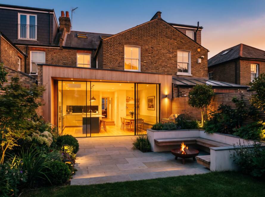 Rear extension with glass doors and garden fire pit at dusk